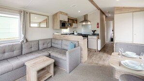 A modern RV interior with a living area, kitchenette, and dining space.