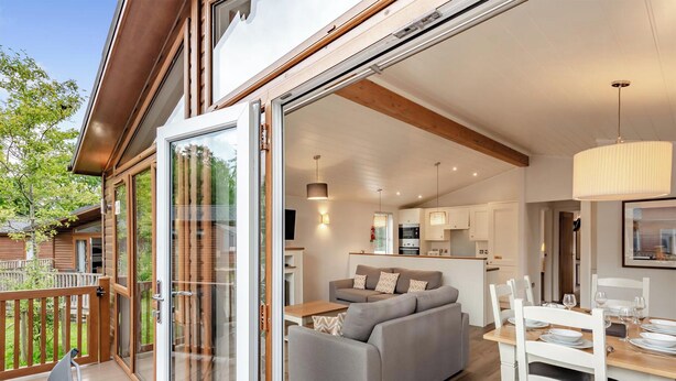 A modern interior with a sofa, dining table, and kitchen area. - Deluxe Lodge with parking, ensuite & decking 4 (Ryde, Nr Bembridge)