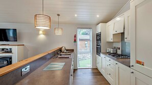 Moderni keittiö, jossa on puinen työtaso, valkoiset kaapit, sisäänrakennettu uuni ja riippuvalaisimet.