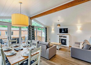 Ein gemütliches Wohnzimmer mit Kamin, eine Essecke mit Tisch für vier Personen und einer Couch.