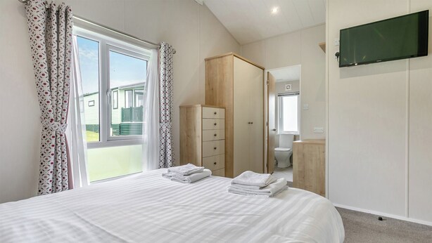 Un dormitorio con cama, armario, televisión y vistas al exterior.