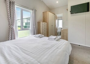 A bedroom with a bed, a wardrobe, a television, and a view of the outside.