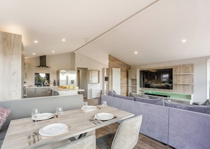 A modern kitchen with a dining area, a built-in TV, and a cozy seating area. - Prestige Lodge, parking, ensuite, decking & SV 4 (Ryde, Nr Bembridge)