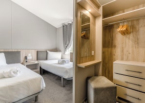 A hotel room with two beds, a bedside table, a mirror, a wardrobe, and a small stool. - Prestige Lodge, parking, ensuite, decking & SV 4 (Ryde, Nr Bembridge)