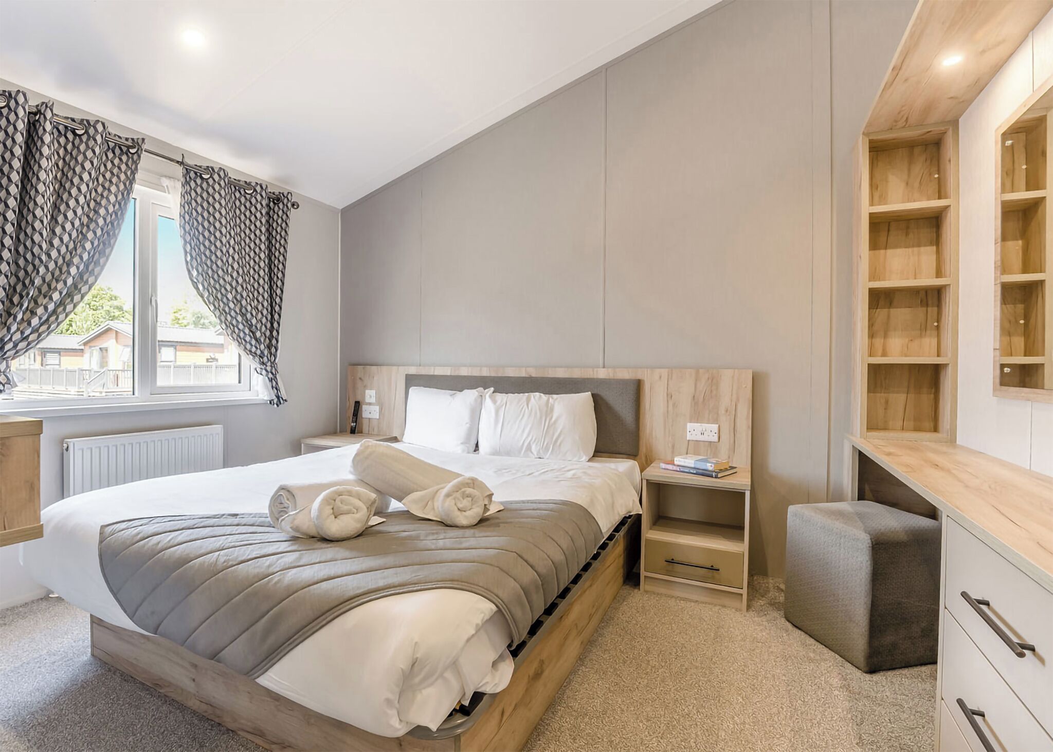 Une chambre moderne avec un cadre de lit en bois, une table de chevet avec une lampe, un petit bureau et une bibliothèque intégrée.