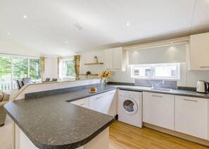 A modern kitchen with a granite countertop, built-in appliances, and a window overlooking greenery. - Prestige Lodge, parking, ensuite, decking & SV 6 (Ryde, Nr Bembridge)