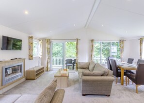 A modern living room with a fireplace, sofa, dining table, and a TV mounted on the wall.