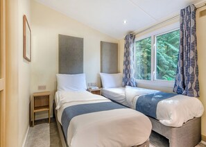 A hotel room with two beds, a small bedside table, a nightstand, and a window with curtains. - Superior Lodge with ensuite & decking (Ryde, Nr Bembridge)