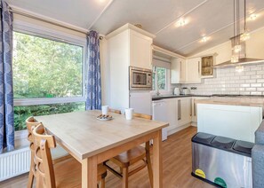 Une cuisine moderne avec des meubles blancs, un four à micro-ondes, un évier et un coin repas comprenant une table et des chaises.