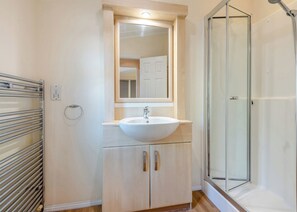 A bathroom with a white sink, a mirror above it, a glass shower enclosure, and a towel rack. - Superior Lodge with ensuite & decking (Ryde, Nr Bembridge)