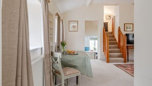 Una habitación con una mesa de comedor, una silla, una escalera y un televisor.