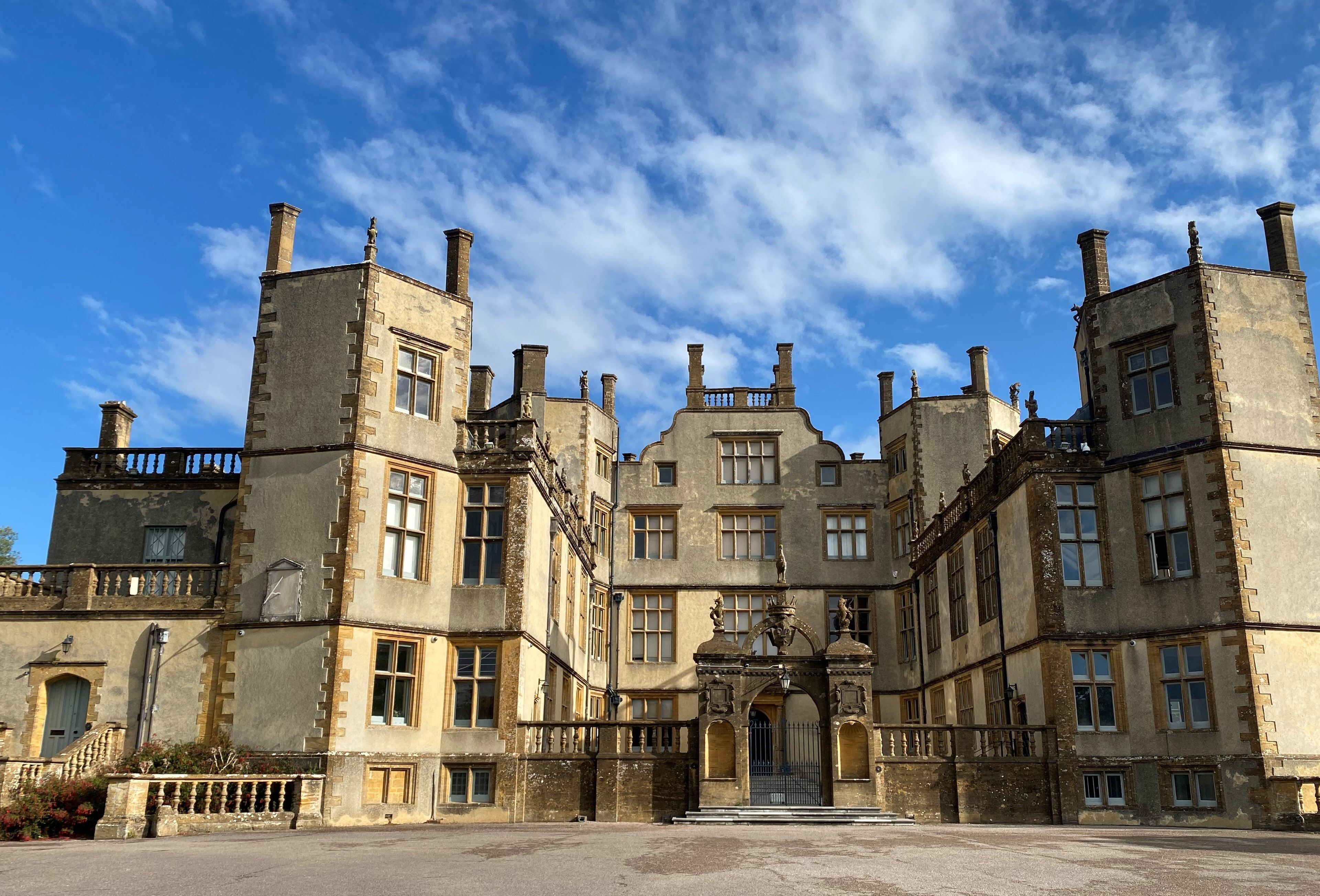 A historic building with multiple towers, a central entrance, and a courtyard.