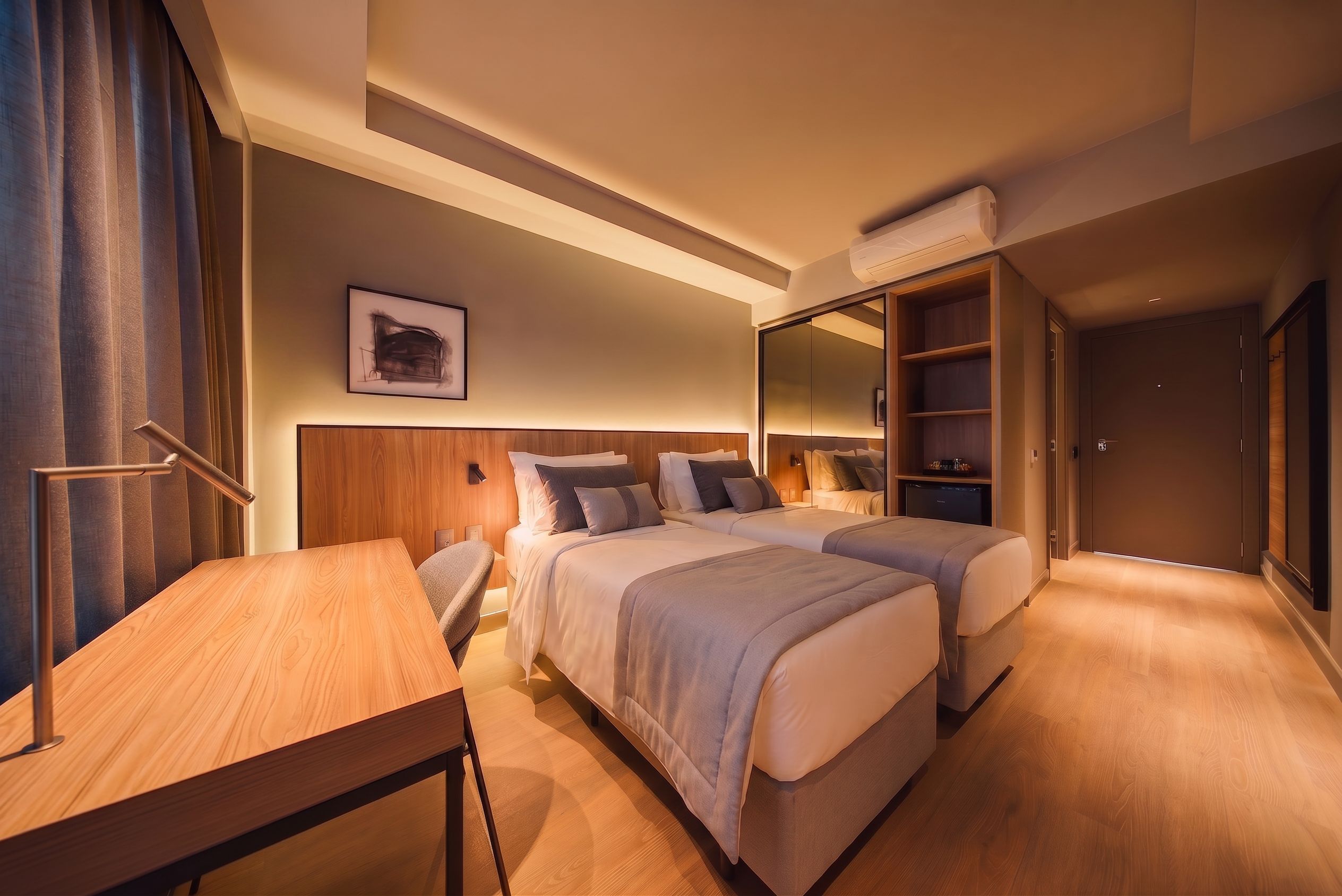 A hotel room with two beds, a desk, a chair, a large mirror, and a wardrobe.