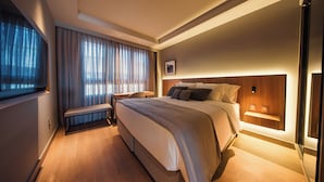A modern hotel room with a large bed, bedside tables, a bench, and a view of the outdoors. - Laghetto Stilo Aeroporto (Porto Alegre)