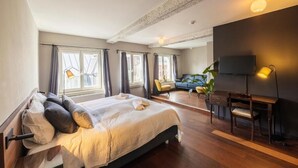 A bedroom with a bed, a desk, a chair, a TV, and large windows. - The Piano Guesthouse - Kwaadham 52 (Ghent)