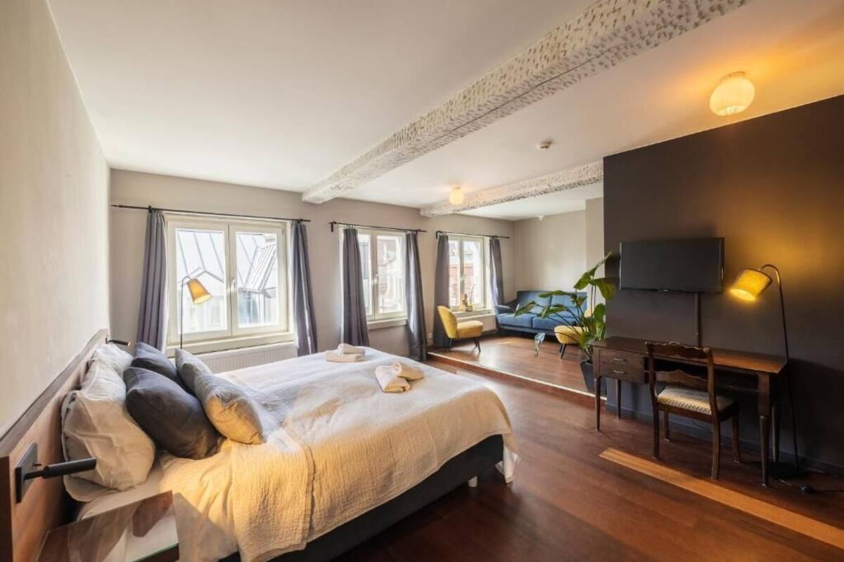 Une chambre à coucher comprenant un lit, un bureau, une chaise, un téléviseur et de grandes fenêtres.