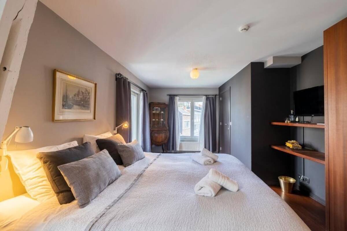 Une chambre à coucher avec un grand lit, une armoire en bois, un téléviseur et un tableau encadré accroché au mur.