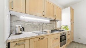 Una cocina moderna con armarios de madera, un lavamanos de acero inoxidable, una tetera y un salpicadero con diseño.