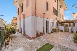 A residential building with a paved courtyard, potted plants, and a small outdoor seating area. - Casa Due Spighe San Sperate (San Sperate)