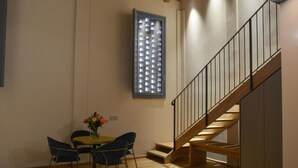 A room with a dining table and chairs, a staircase, and a window with a grid pattern. - Maranello Resort Borgo della Montina (Maranello)