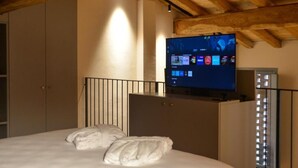 A bedroom with a bed, a TV mounted on the wall, and a window with blinds. - Maranello Resort Borgo della Montina (Maranello)