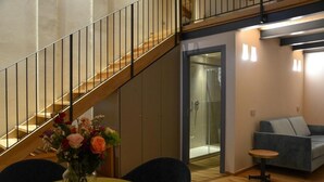 A modern interior with a staircase, a sofa, a small table, and a vase with flowers. - Maranello Resort Borgo della Montina (Maranello)