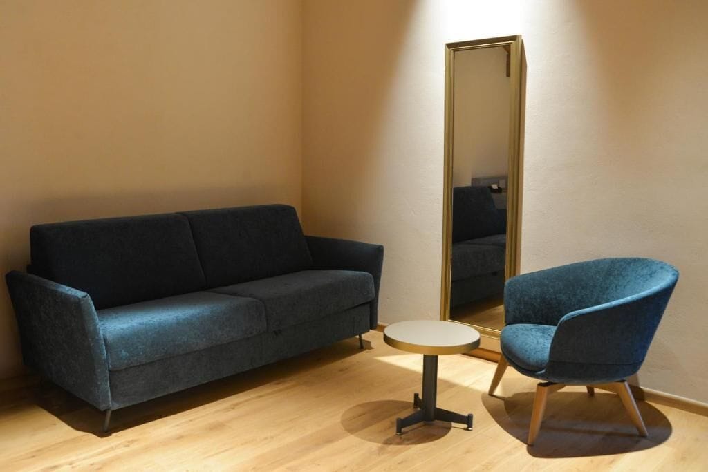 Una habitación con sofá, una silla y una mesa redonda.