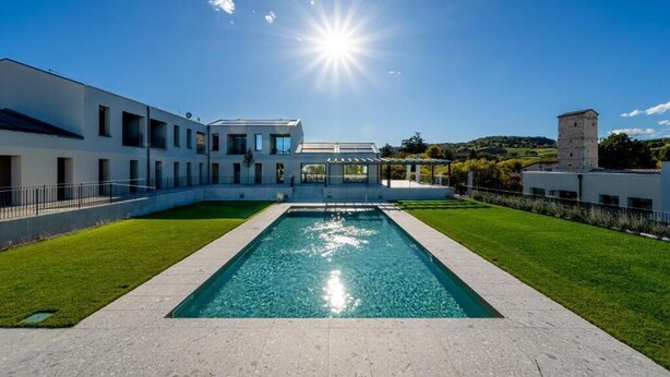 A modern building with a swimming pool, a tower, and a clear blue sky. - Maranello Resort Borgo della Montina (Maranello)