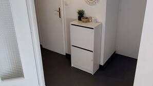A hallway with a white door, a white dresser, a mirror, and a hanging light fixture. - Studio "Les Cascades" with Mountain View, Balcony, and Wi-Fi (Gaillard)