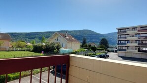 A residential area with a balcony, a parked car, and a building with multiple balconies. - Studio "Les Cascades" with Mountain View, Balcony, and Wi-Fi (Gaillard)