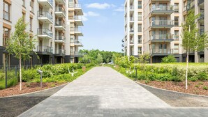 Un edifici d'apartaments modern amb un passeig central, balcons i vegetació.