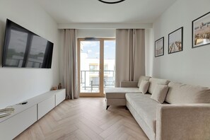 A modern living room with a sofa, TV, and artwork on the wall. - RentPlanet - Apartament Filarskiego (Gdańsk)