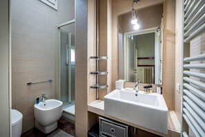 A modern bathroom with a bidet, a large sink, a mirror, and a towel rack. - Servi B (Florence)