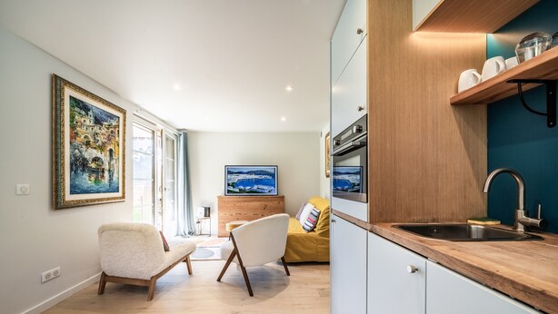 A modern kitchen with a wooden countertop, a sink, and a dining area with chairs. - Apartment “Au Pied Des Pistes - Petit Châtel” with Mountain View, Private Terrace & Wi-Fi (Châtel)