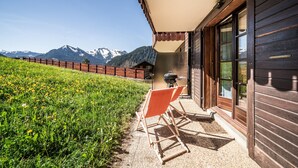 A wooden cabin with a patio, outdoor seating, and a mountain view. - Apartment “Au Pied Des Pistes - Petit Châtel” with Mountain View, Private Terrace & Wi-Fi (Châtel)