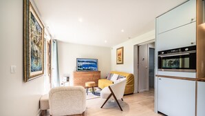 A modern living room with a sofa, armchair, and a dining area with a table and chairs. - Apartment “Au Pied Des Pistes - Petit Châtel” with Mountain View, Private Terrace & Wi-Fi (Châtel)