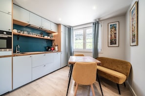 Una cocina moderna con armarios azul claro, encimera de madera y un comedor con mesa y sillas.