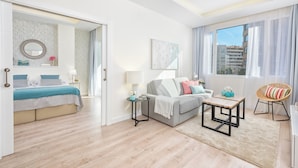 A modern hotel room with a bed, a sofa, a small table, a chair, and a window with curtains. - Solaga - Centro Alameda (Málaga)