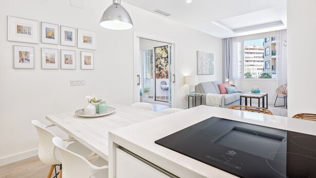 A modern kitchen with a built-in stove, white cabinetry, and a dining area with a table and chairs. - Solaga - Centro Alameda (Málaga)
