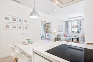 A modern kitchen with a built-in stove, white cabinetry, and a dining area with a table and chairs. - Solaga - Centro Alameda (Málaga)