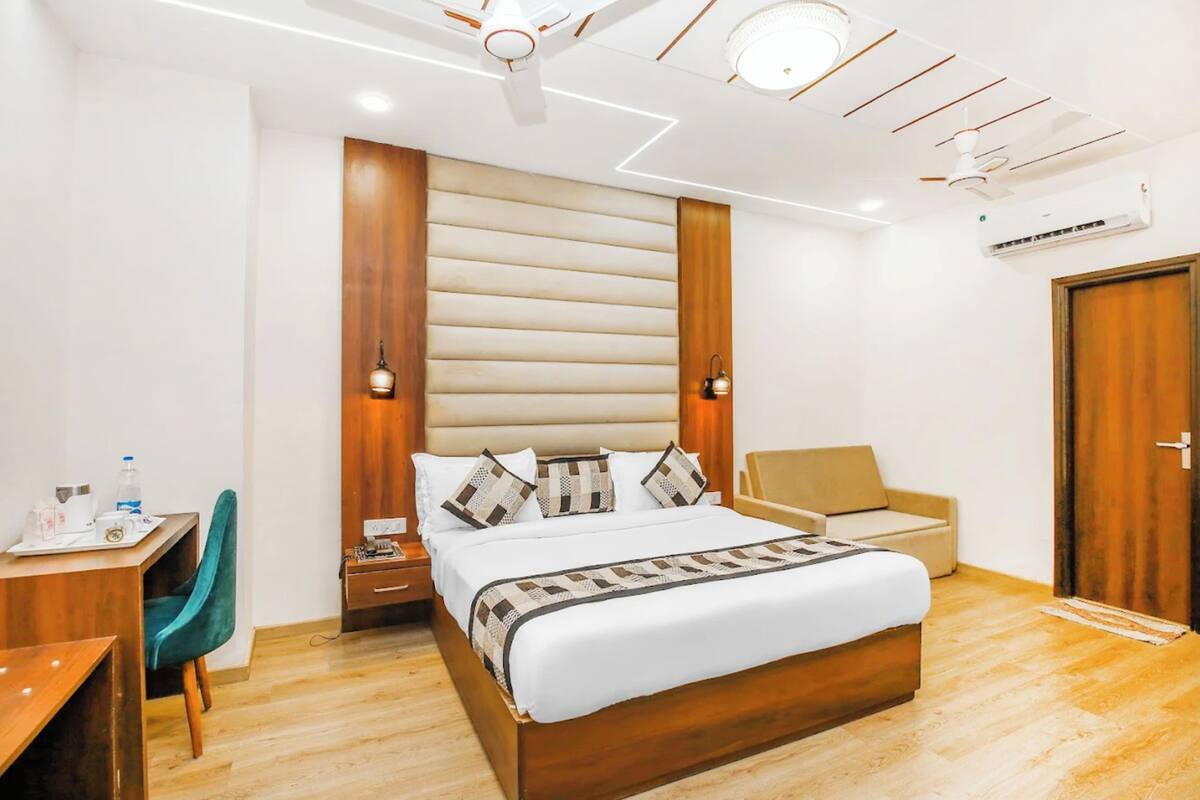 Ein Hotelzimmer mit Bett, Schreibtisch, Stuhl, Kleiderschrank und Deckenventilator.