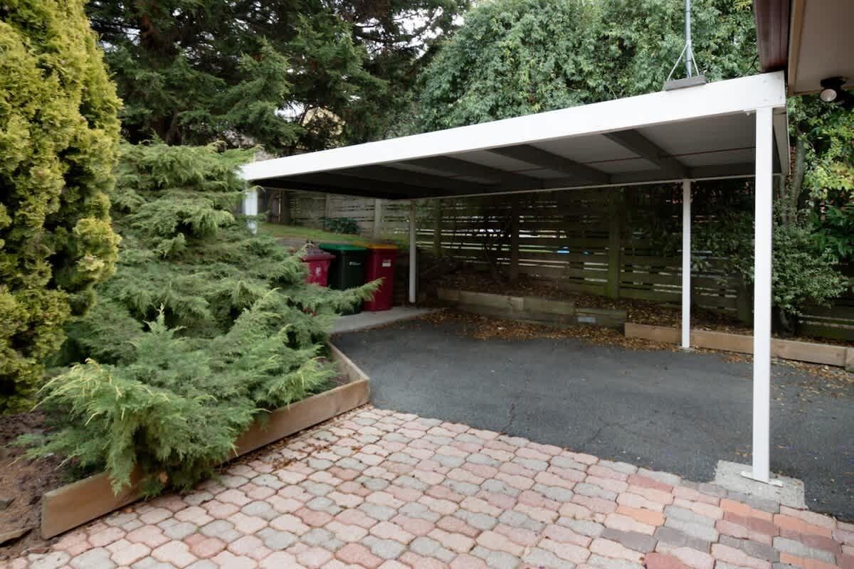 Un espace extérieur abrité, doté d’un sol pavé, entouré de verdure et d’une clôture en bois.