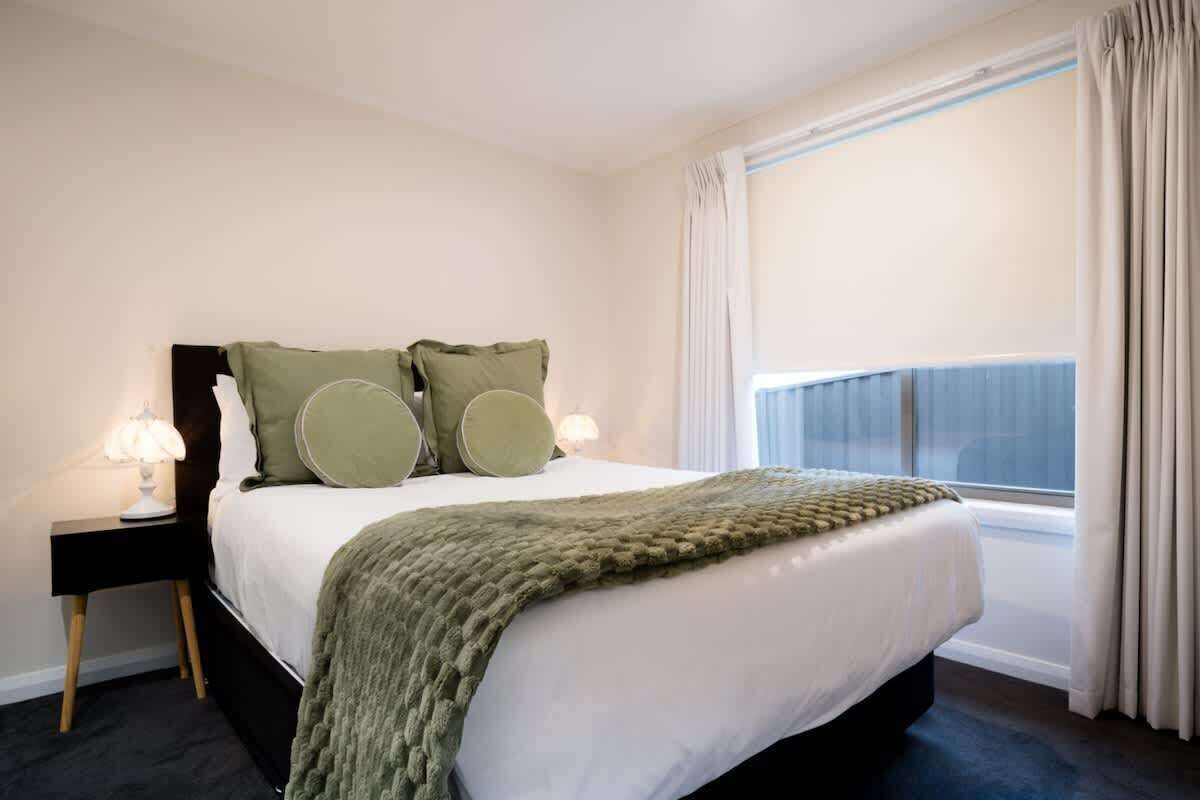 Une chambre d’hôtel avec un lit, des tables de chevet, une fenêtre avec des rideaux et une vue.