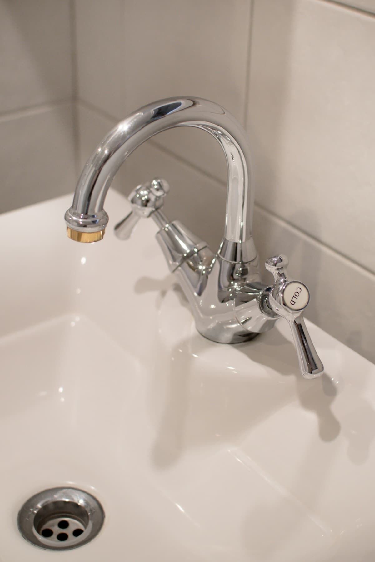 Un lavamanos de baño con grifo cromado y un solo mando.