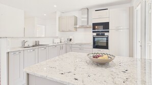 A modern kitchen with white cabinetry, a granite countertop, a built-in oven, and a coffee maker. - Lovely house with pool for 8 (Les Sables-d´Olonne)