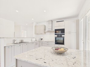 A modern kitchen with white cabinetry, a granite countertop, a built-in oven, and a coffee maker. - Lovely house with pool for 8 (Les Sables-d´Olonne)