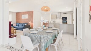 A modern living space with a dining area, kitchen, and a brick accent wall. - Lovely house with pool for 8 (Les Sables-d´Olonne)