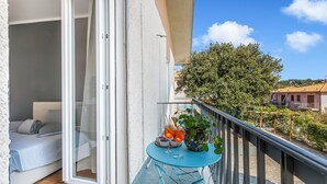 A balcony with a bed, a table with drinks and a plant, and a view of the surrounding area. - Villa Talamone With Beautiful Sea View (Orbetello)