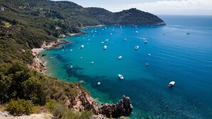 A coastal landscape with boats on clear blue water, rocky terrain, and dense greenery. - Villa Talamone With Beautiful Sea View (Orbetello)