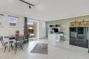 A modern kitchen with a built-in oven, a dining area with a table and chairs, and a view of the outside.
